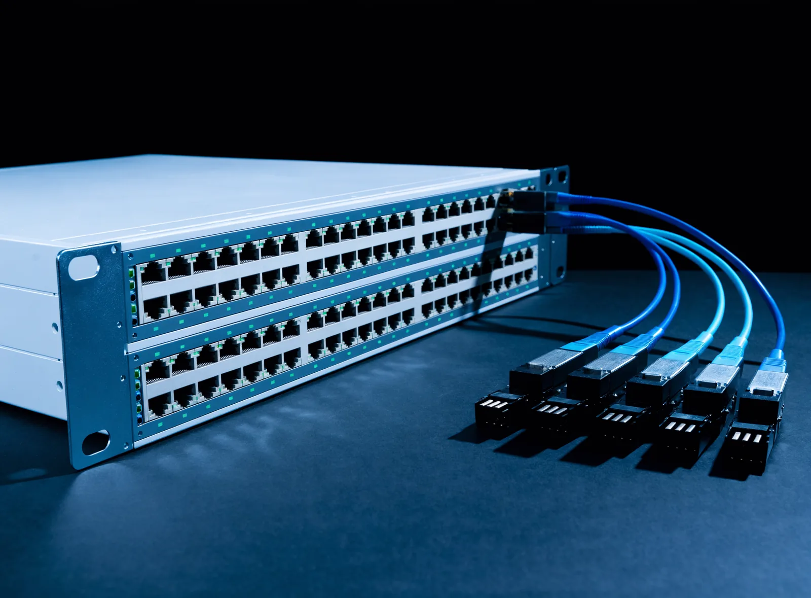 48 port rackmount network switch with illuminated port LEDs alongside fiber optic SFP transceivers